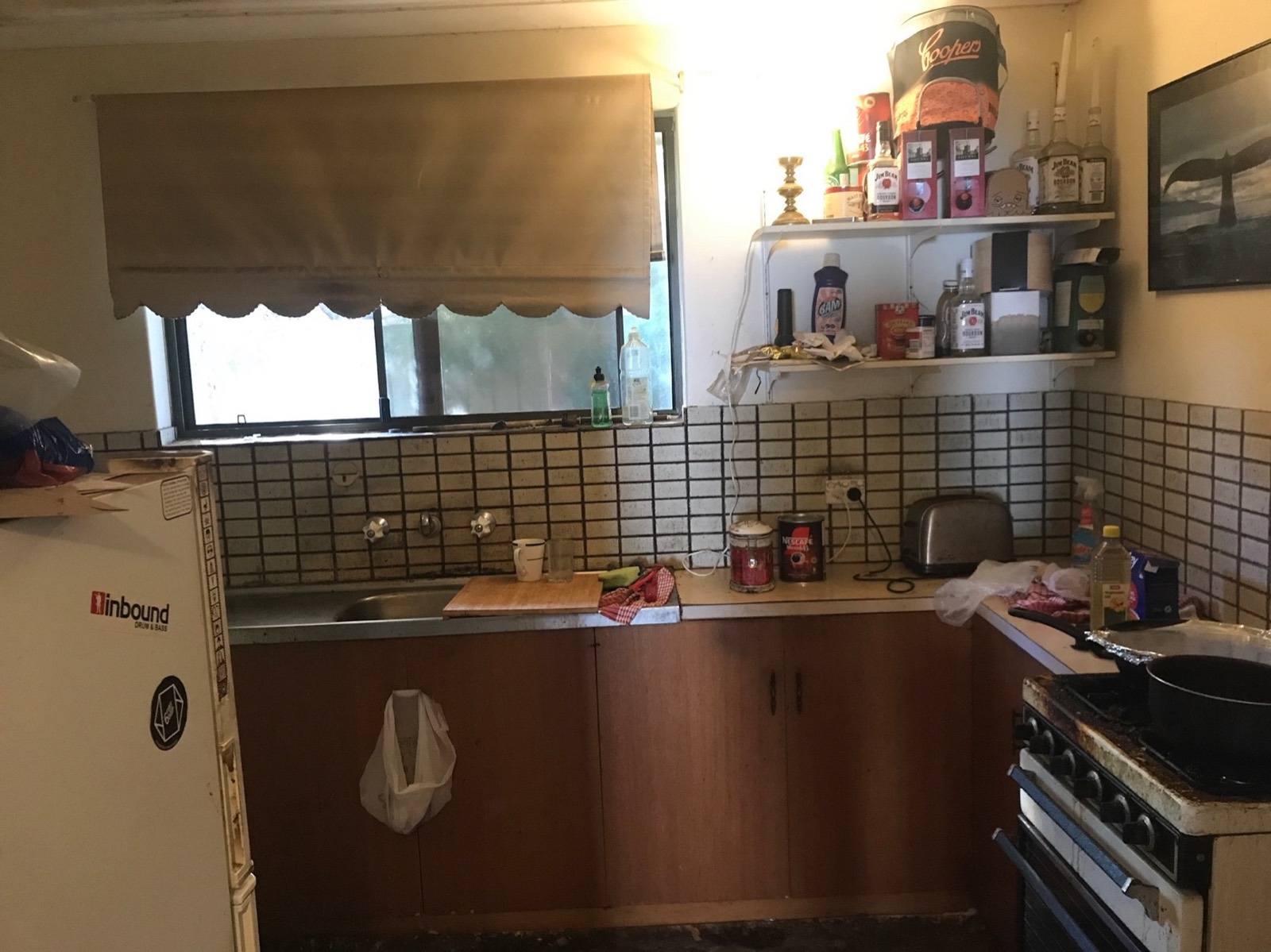 Kitchen before: dated timber cabinets and tiled splashback