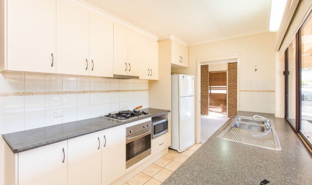 Rental kitchen before: freestanding fridge and older cabinetry