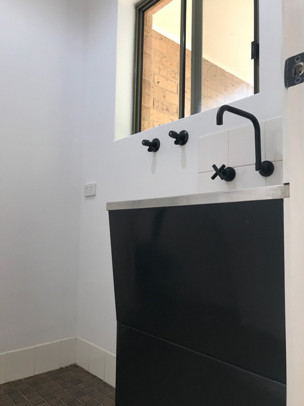 Laundry after: freshly painted cabinet and matte black tapware