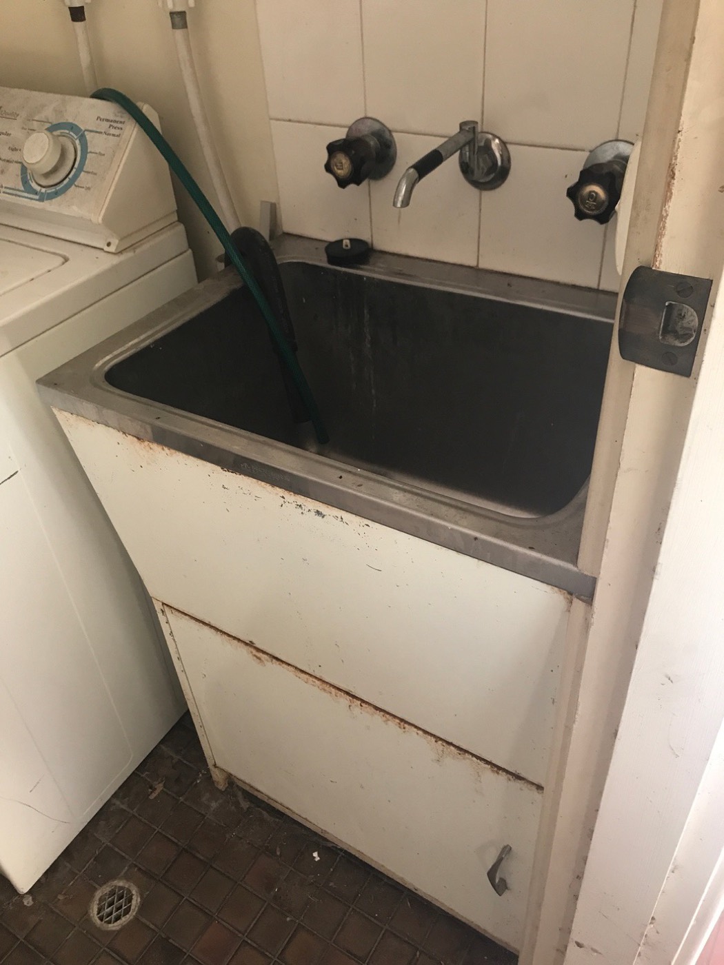Laundry before: rusted cabinet and old tapware